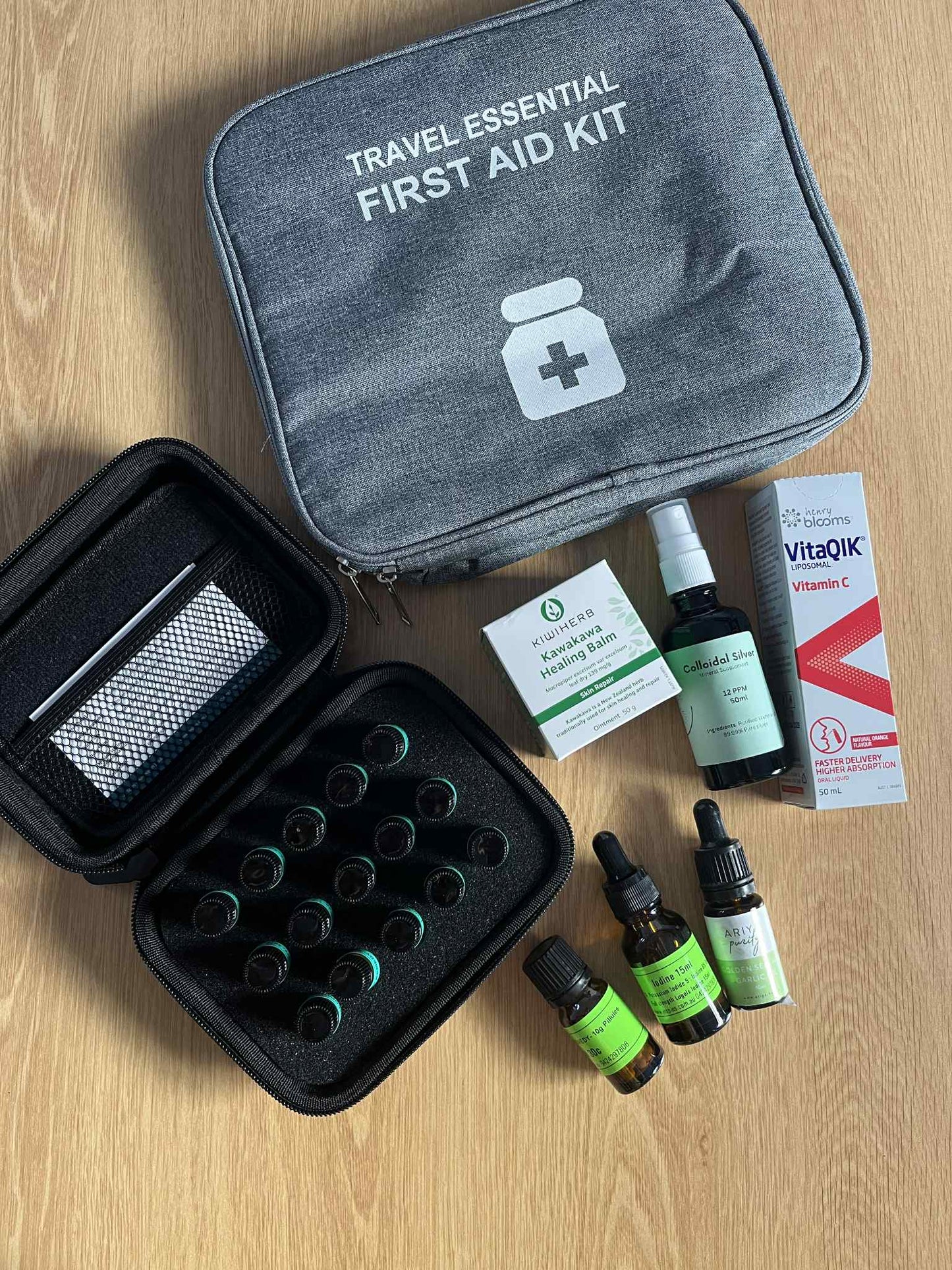 Travel essential naturopathic and homeopathic naturl first aid medicine kit flat laid on wooden table.